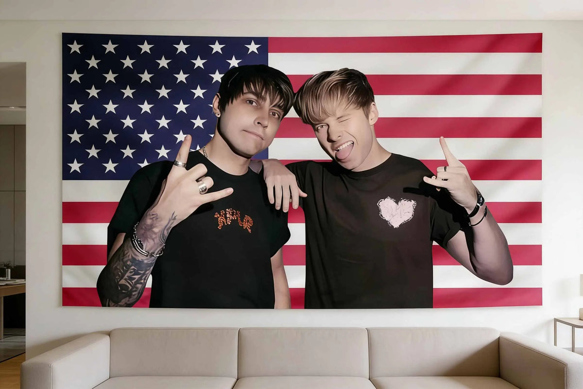 Two young men pose in front of an American flag tapestry wall art.
