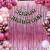 A pink and gold balloon backdrop with a green banner reading Happy Birthday