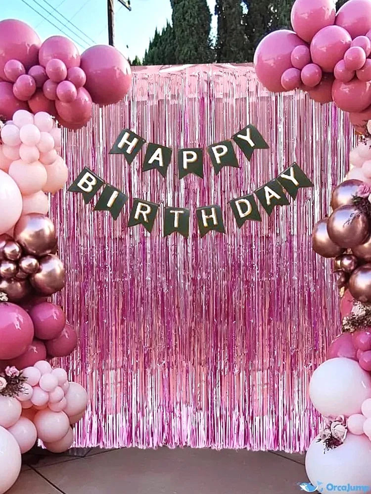 A pink and gold balloon backdrop with a green banner reading Happy Birthday