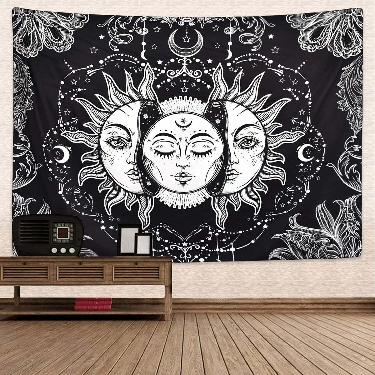 A black tapestry featuring intricate white line art of the sun and moon faces surrounded by celestial elements.