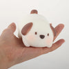 A hand holds an adorable pink pig mochi squishy stress relief toy with brown ears and a cute face.