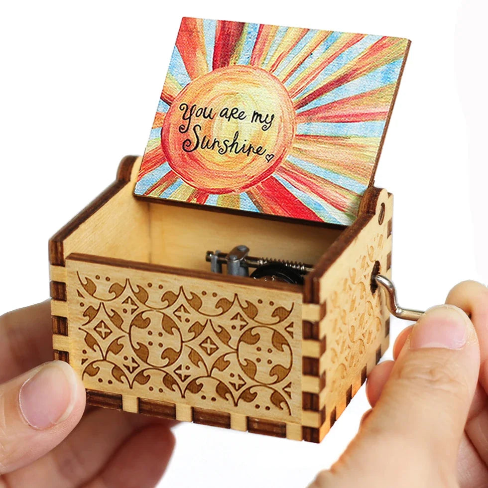 A carved wooden music box with a lid featuring a sunburst design and a message