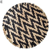 A round wall decor hanging made of black and natural straw woven in a chevron pattern.