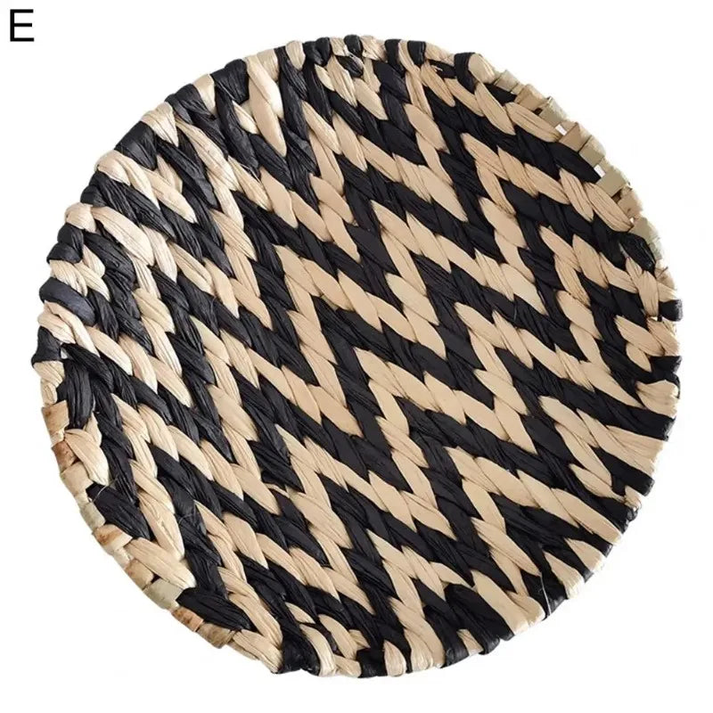 A round wall decor hanging made of black and natural straw woven in a chevron pattern.
