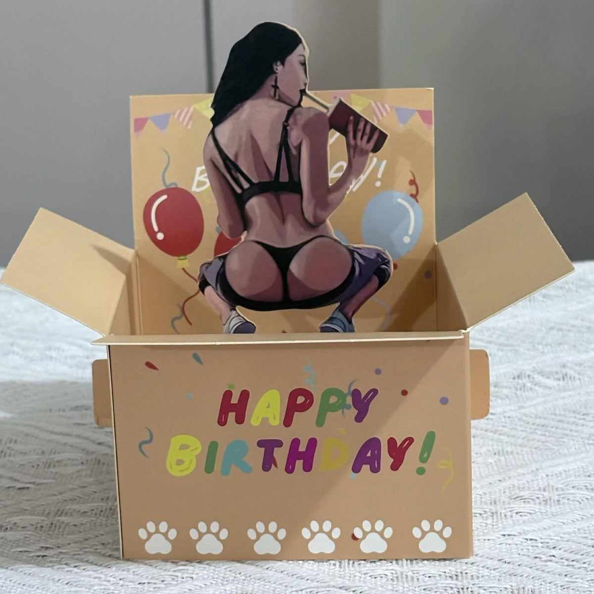A humorous 3D pop-up birthday card featuring a woman, heart balloons, and confetti.