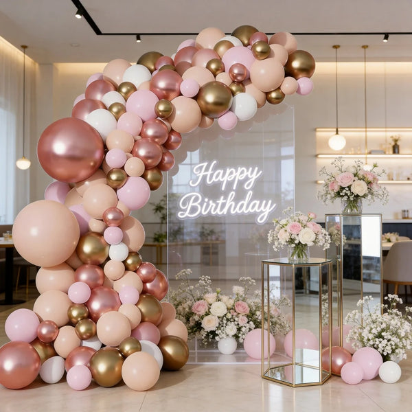 Un grand guirlande de ballons rose, or rose et beige disposés en arche.