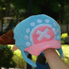 A light blue knit cap plush toy featuring a pink brim and white pom-pom details.