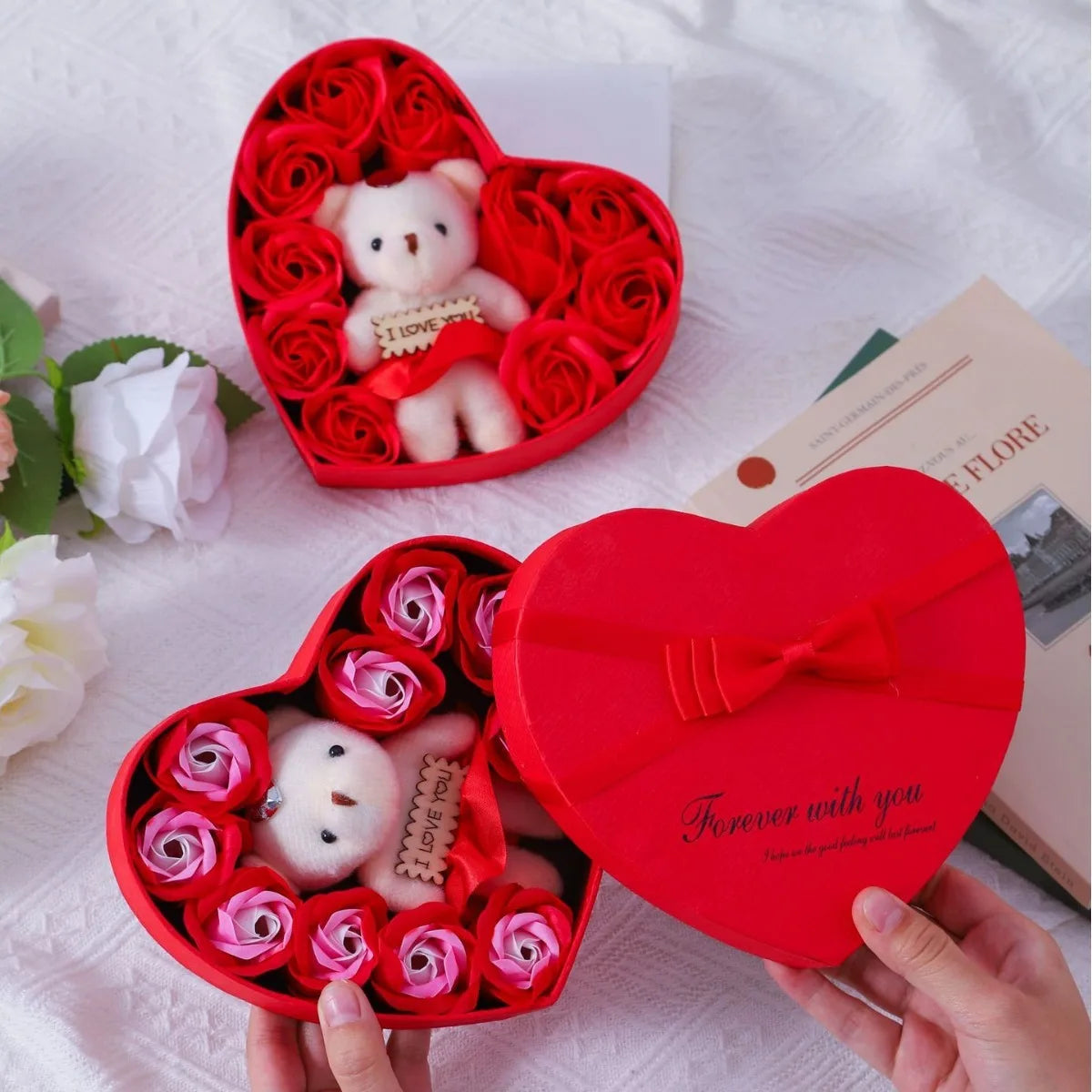 A red heart-shaped box filled with pink roses and a white bear soap, presented as a romantic gift.