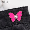 Pink butterfly button accessory attached to a black denim garment.