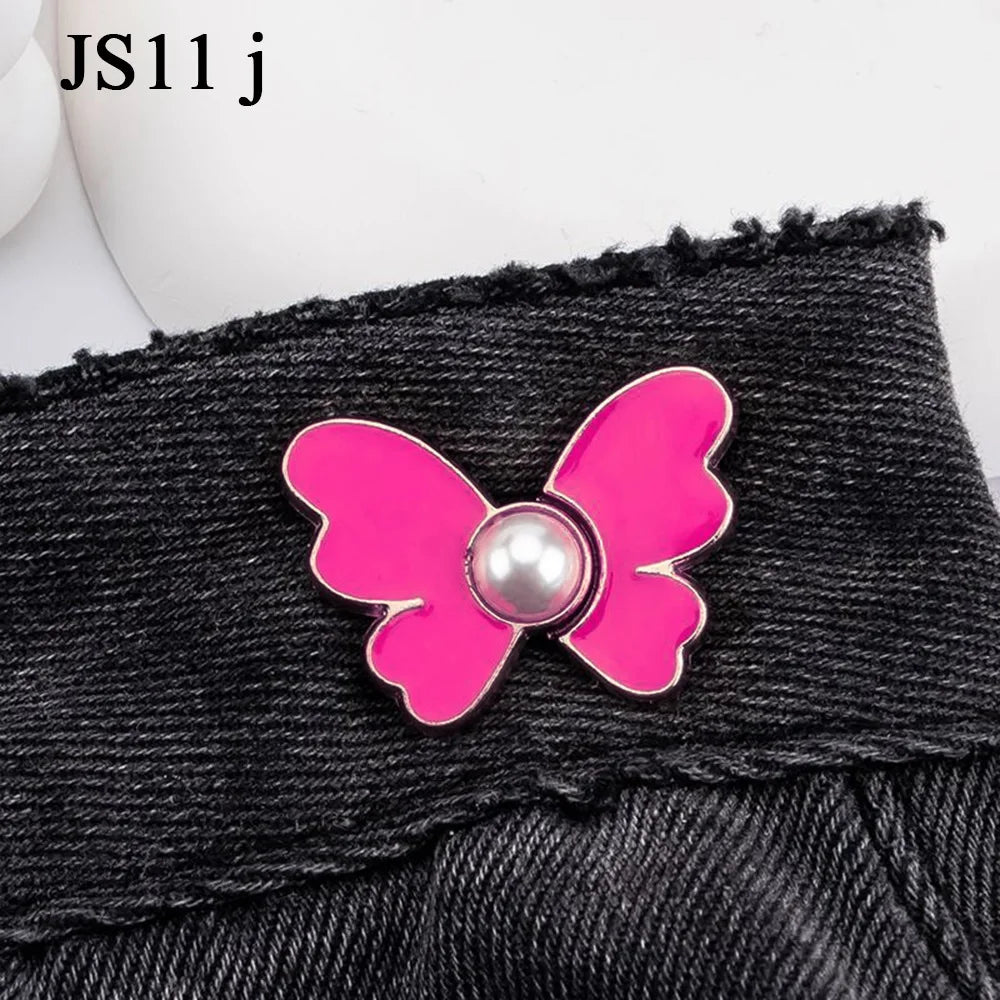 Pink butterfly button accessory attached to a black denim garment.