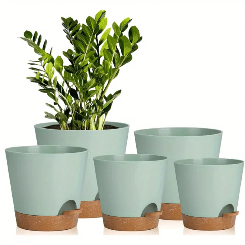 A set of five light green self-watering plant pots with drainage holes sitting on a surface.