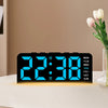 A black digital alarm clock displaying 22:38 with a bright blue light, placed on a white surface next to a vase of tulips.