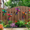 Set of four metal hummingbird wall decor featuring vibrant iridescent colors against a wooden fence backdrop.