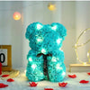 Heller blauer künstlicher Rosen-Teddybär mit leuchtenden LED-Lichtern auf weißem Untergrund.