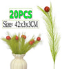 A bundle of green Christmas tree decor picks with red berries in a white vase.