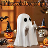 A white ghost figurine with a sassy hand gesture is displayed among Halloween decorations like a pumpkin and a witch hat.