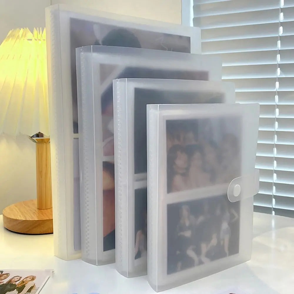 A stack of clear photo albums with transparent card holders displayed next to a lamp.