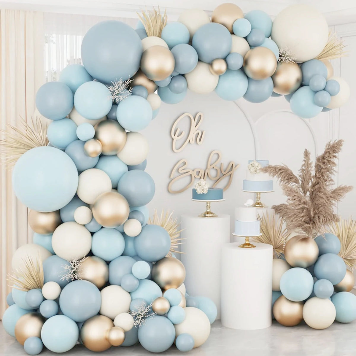 A floral arch made of light blue and gold latex balloons decorated with dried pampas grass and white accents.