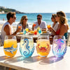 Four stemless wine glasses filled with glowing blue and orange liquid featuring sea creature designs