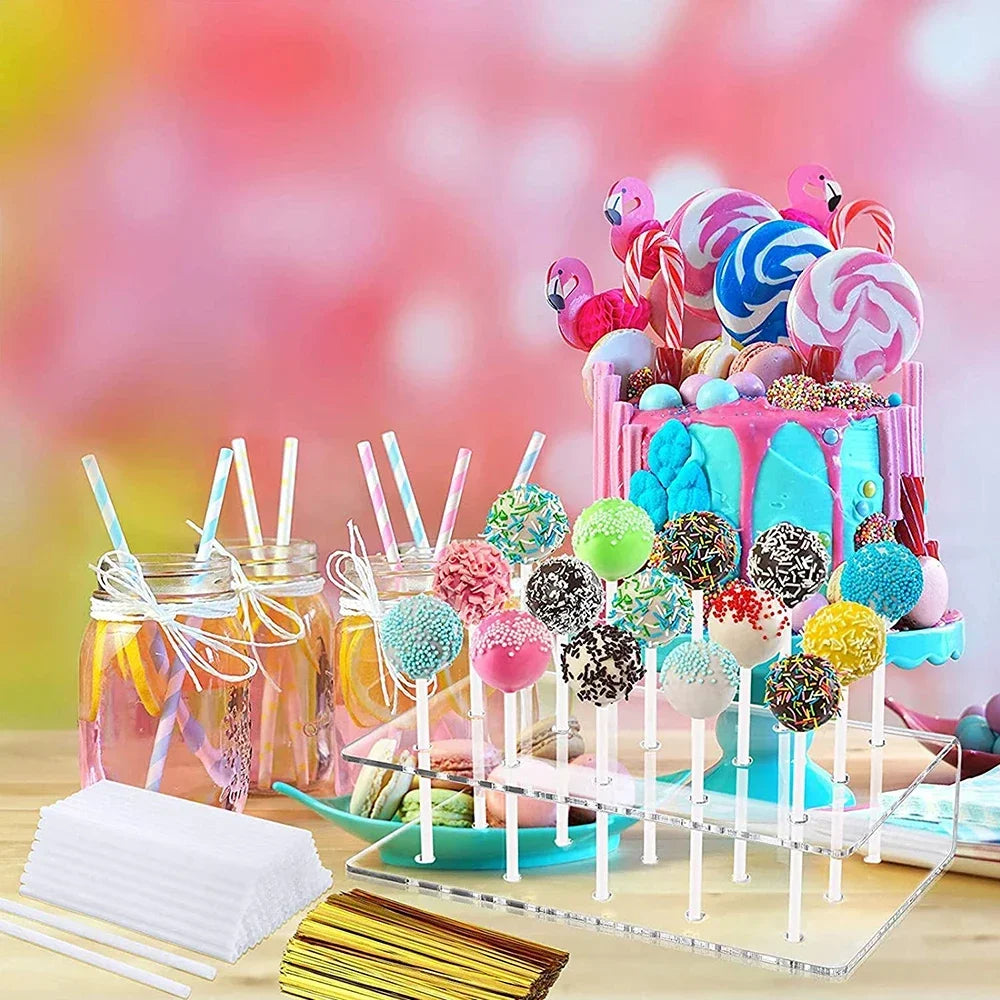 A clear acrylic display stand holds colorful cake lollipops and candies on sticks.