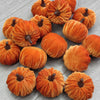 A set of ten small, fuzzy orange velvet pumpkin decorations for fall and holiday styling.