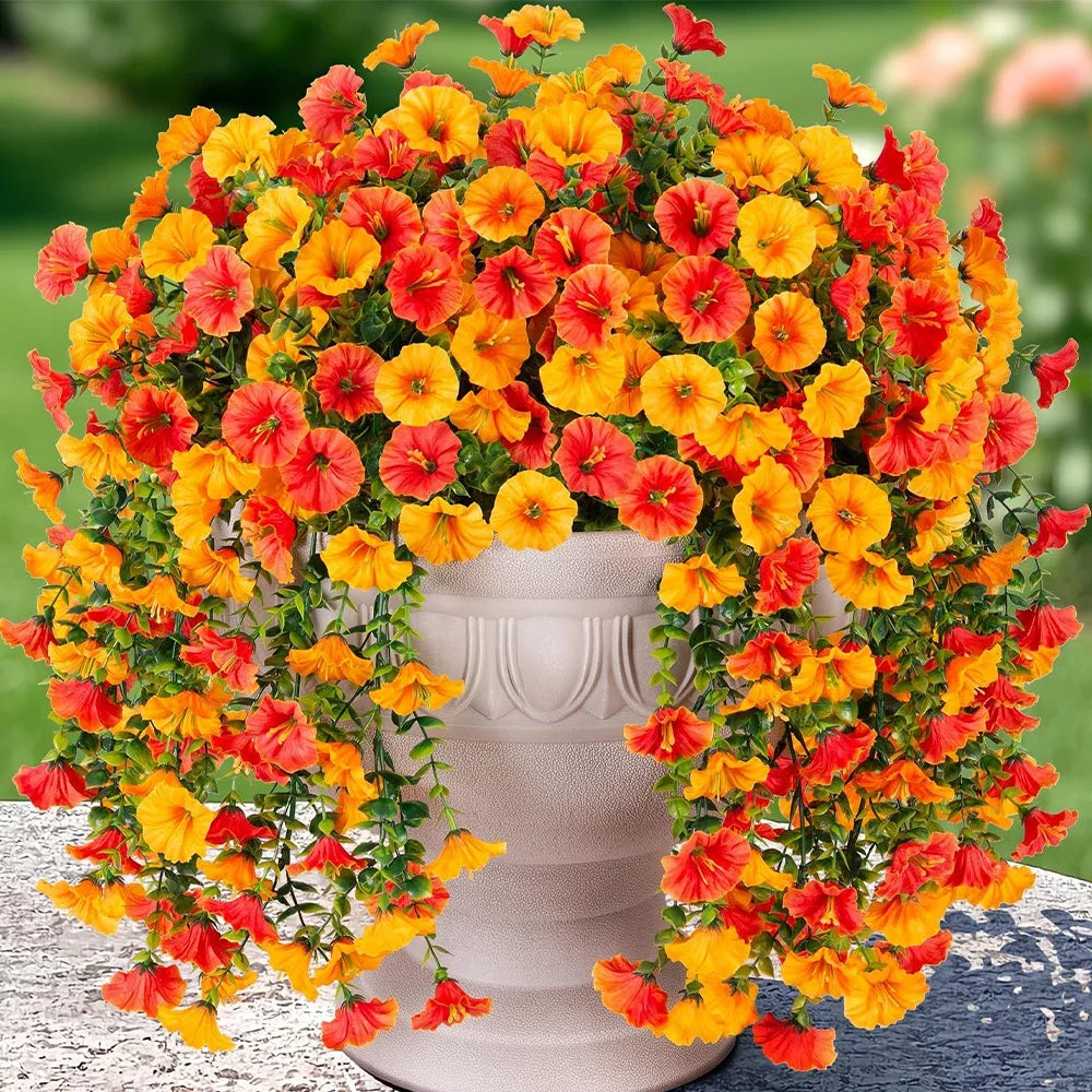 A vibrant arrangement of artificial hanging morning glory flowers in shades of orange and red with green eucalyptus leaves.