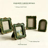 Antique gold finish resin picture frame with carved details, displayed on a white surface.