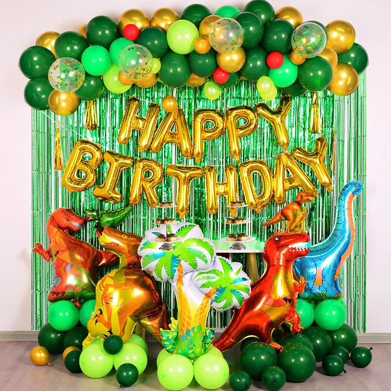 A green and gold balloon arch featuring foil balloons shaped like dinosaurs against a shimmering tinsel curtain.