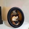 A round black photo frame holds a portrait of a fox wearing a hat and bow tie.