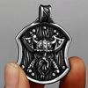 A silver stainless steel Viking warrior shield pendant is held by a hand against a gray background.