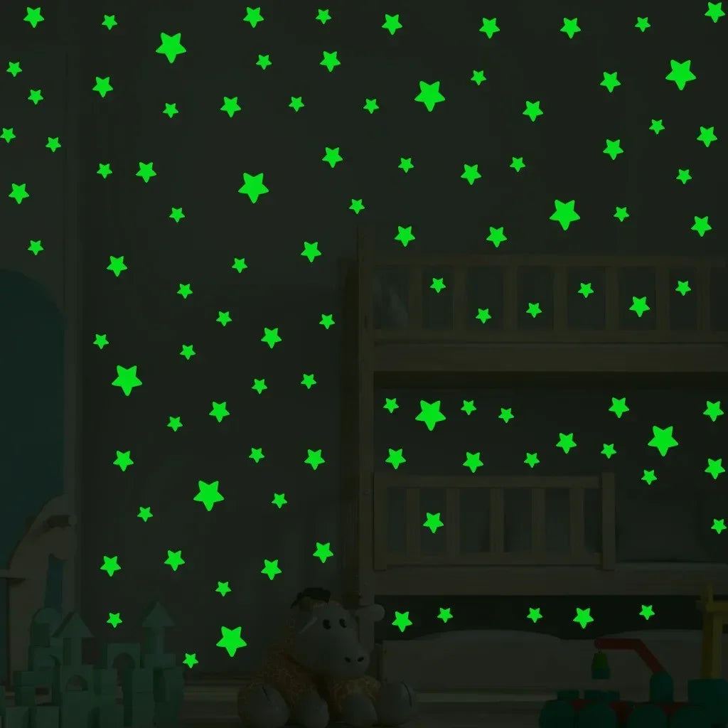 A dark room decorated with green glow-in-the-dark star decals on a wall and a wooden shelf.
