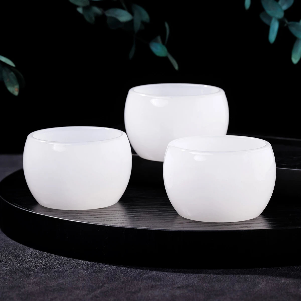 Three smooth white crystal agate healing bowls displayed on a black surface against a dark background.