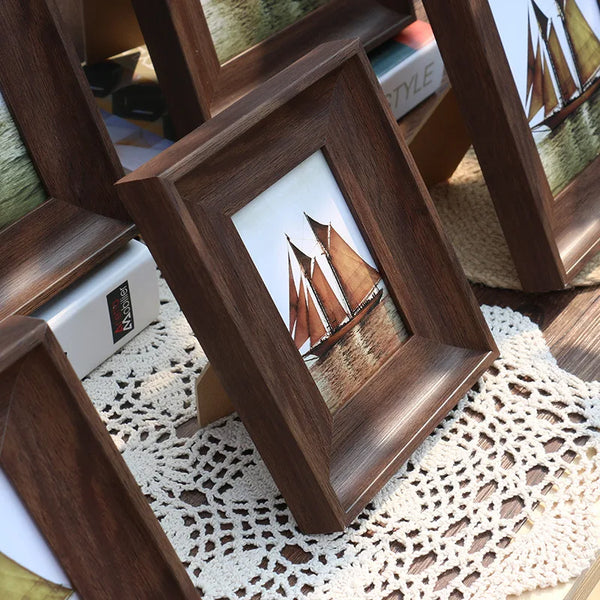 A dark wood vintage resin photo frame displaying a sailboat silhouette on water, resting on a crocheted mat.