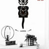 A black cartoon cat wall clock with a swinging tail is displayed on a wooden surface.