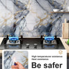 Black induction cooktop with blue flame display set against a marble wall background.