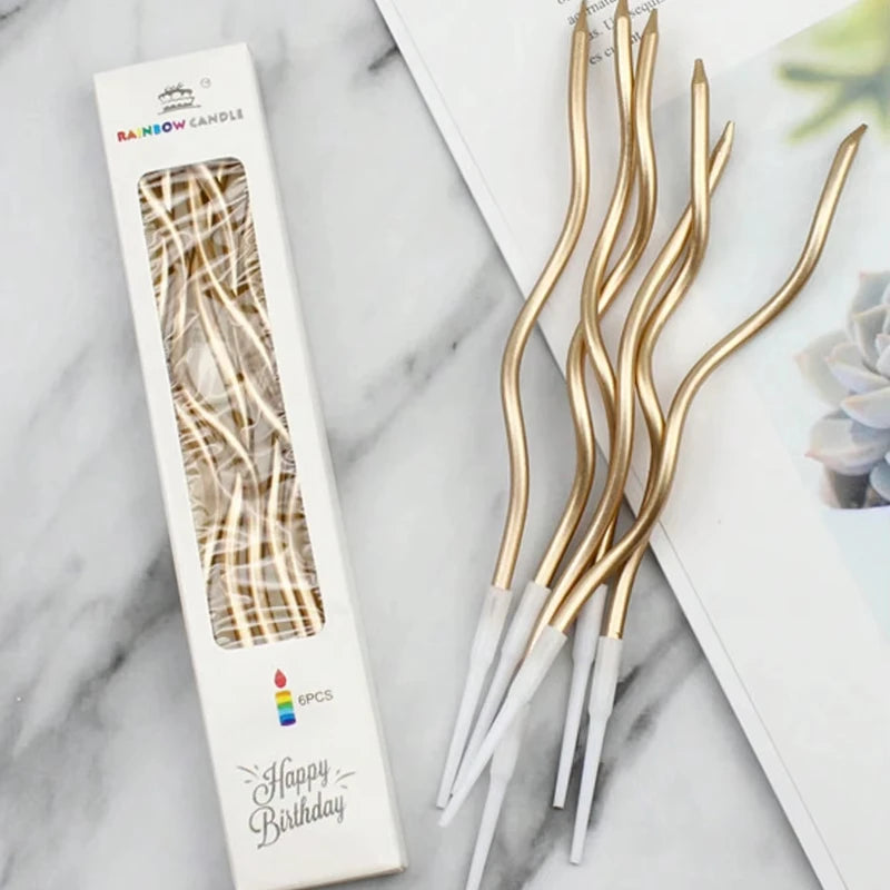 A set of gold and white curved decorative birthday candles in a box with a marbled pattern.