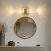 Modern bubble crystal LED wall sconces mounted above a round mirror on a white wall.