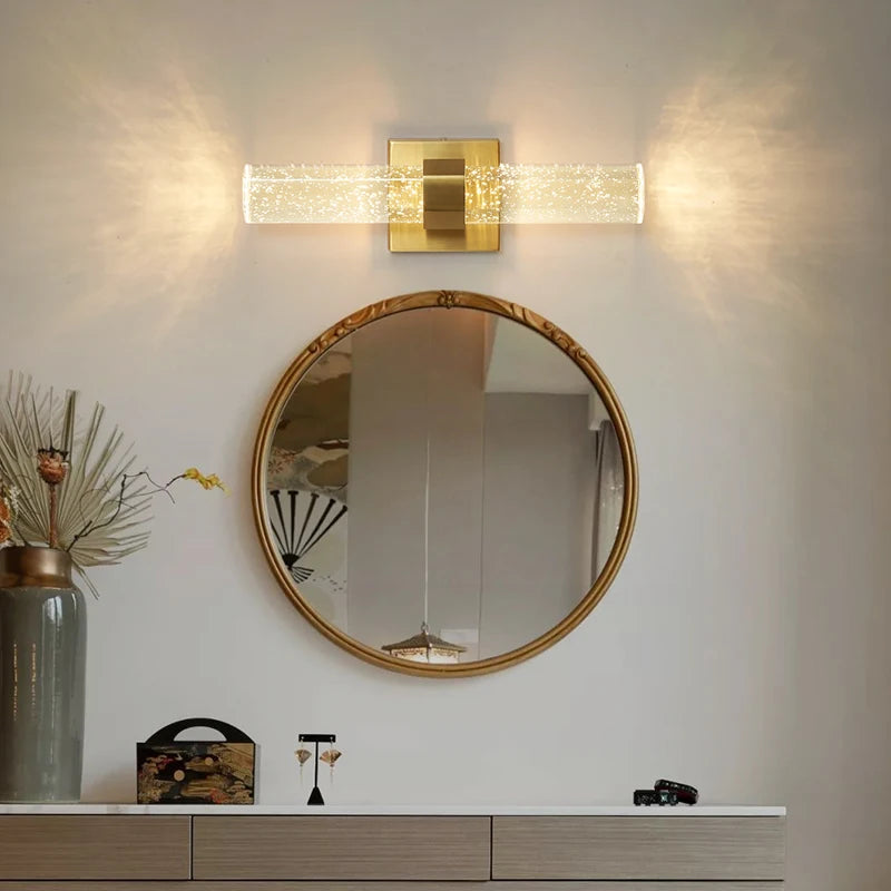 Modern bubble crystal LED wall sconces mounted above a round mirror on a white wall.