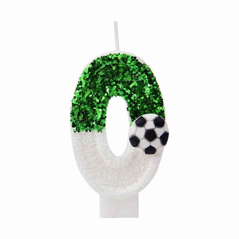 White candle shaped like the number zero covered in green glitter and a soccer ball design