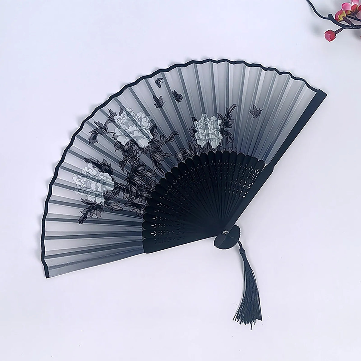 A black vintage bamboo folding fan with sheer fabric and floral decorations shown against a white background.