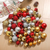 Assorted Christmas tree ornaments and baubles in various colors including gold silver red and green on a light wooden surface