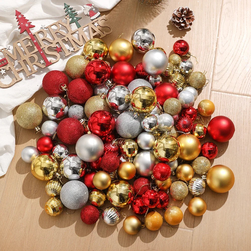 Assorted Christmas tree ornaments and baubles in various colors including gold silver red and green on a light wooden surface