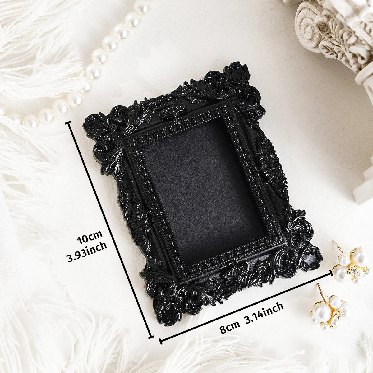 Black ornate resin frame wall decor with a rectangular opening displayed on a white surface.
