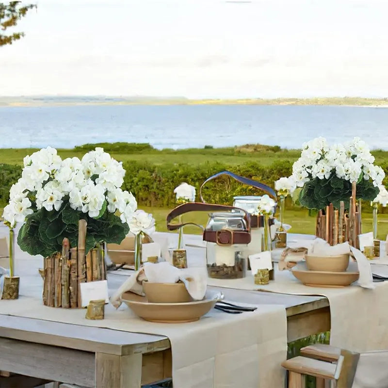 A table setting featuring white flowers and greenery for an outdoor event.