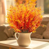 A bouquet of bright orange and yellow artificial lavender stems in a white ceramic vase