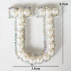 A white alphabet letter U made of pearl and rhinestone embellishments.