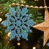 A close-up of a Christmas tree decorated with shimmering blue snowflake ornaments and a gold star ornament.