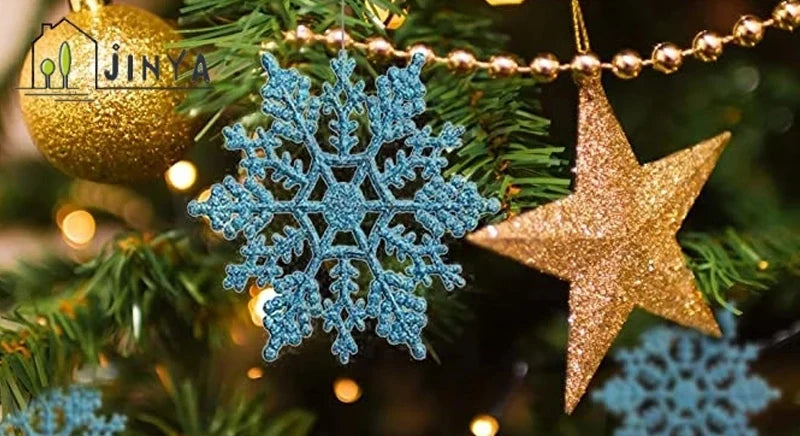 A close-up of a Christmas tree decorated with shimmering blue snowflake ornaments and a gold star ornament.