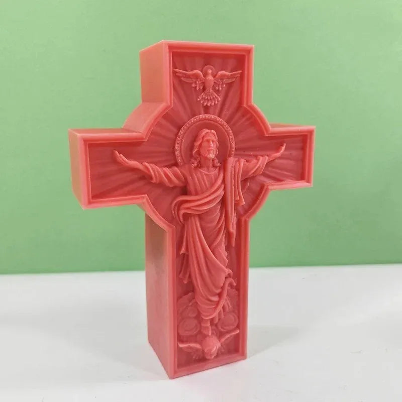 A pink silicone mold of a religious Jesus cross with an angel above and a depiction of Jesus in the center.