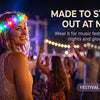 A woman wearing an LED flower crown headband with glowing lights at a night music festival.